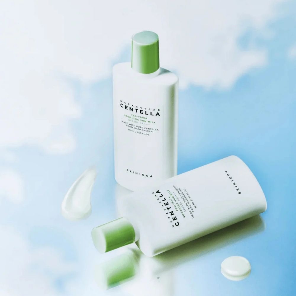 Zwei Flaschen Madagascar Centella Tea-Trica Soothing Sun Milk SPF50+ PA++++, eine liegend, mit Produktprobe.