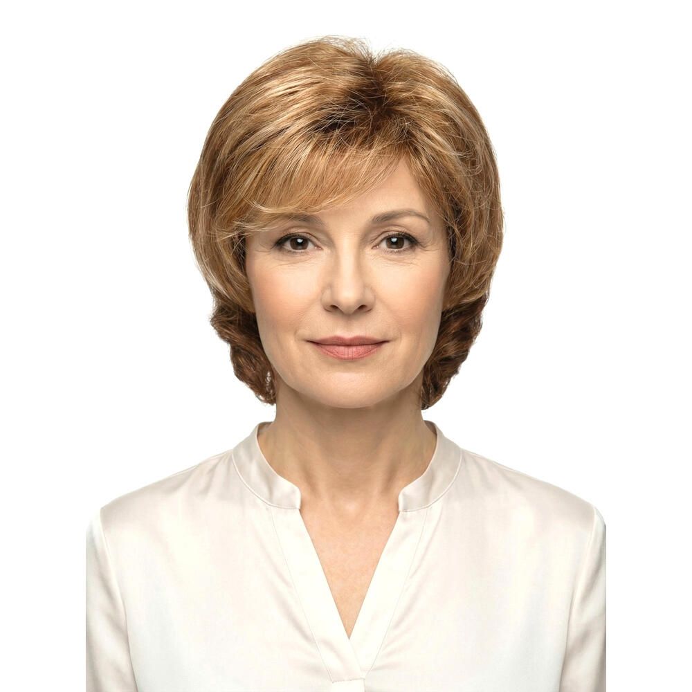 Frau mit Perücke, blond-braune Haare, Frontansicht. Hellbraune Strähnen, schulterlange Frisur. Trägt eine helle Bluse.