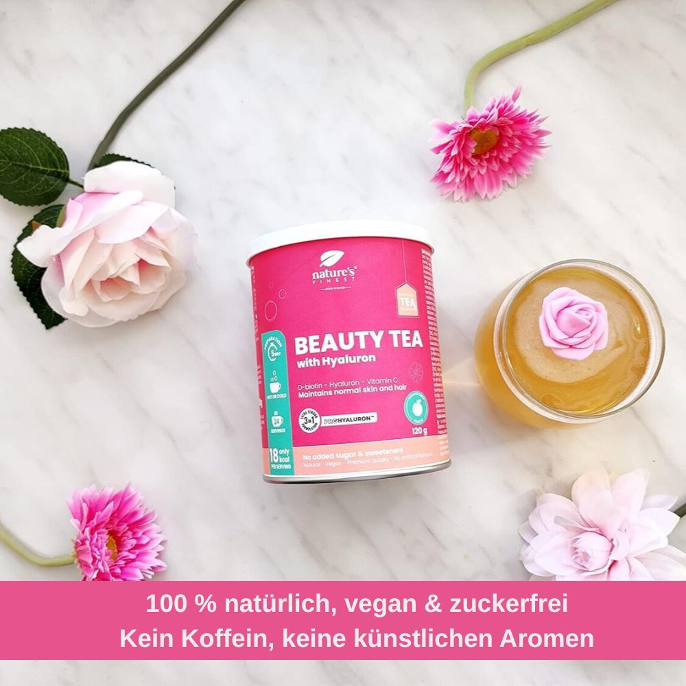 Dose Nature's Finest Beauty Tea mit Hyaluron, umgeben von Blumen und einem Glas Tee.