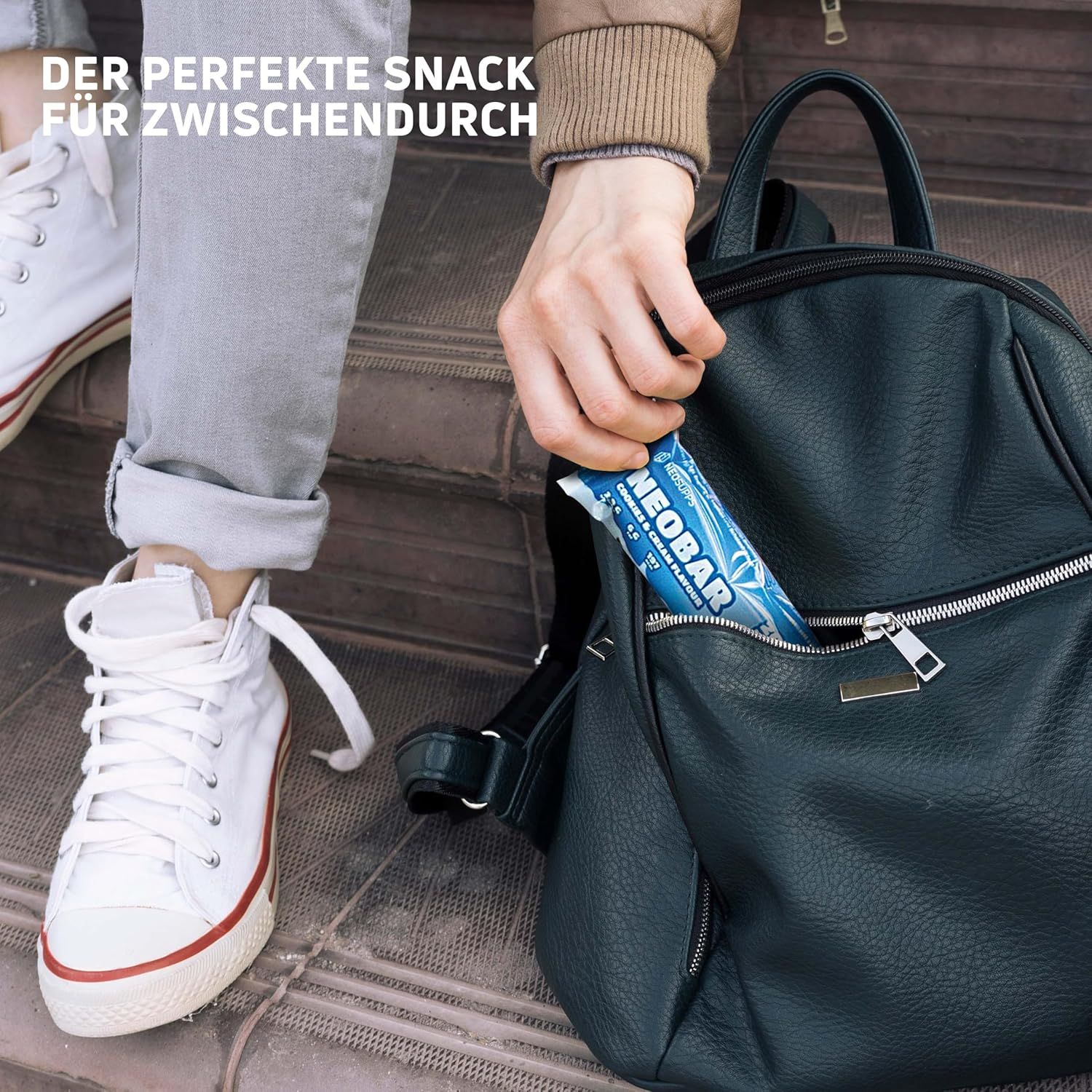 Person steckt NeoBar Proteinriegel in eine schwarze Handtasche. Aufschrift: NeoBar Cookies & Cream Flavour.