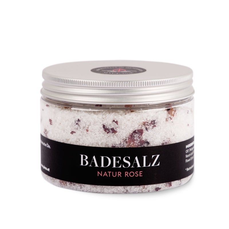 Rundes Glas mit Badesalz. Schwarzes Etikett mit "Badesalz Natur Rose". Salz mit Blütenblättern. Silberfarbener Deckel.