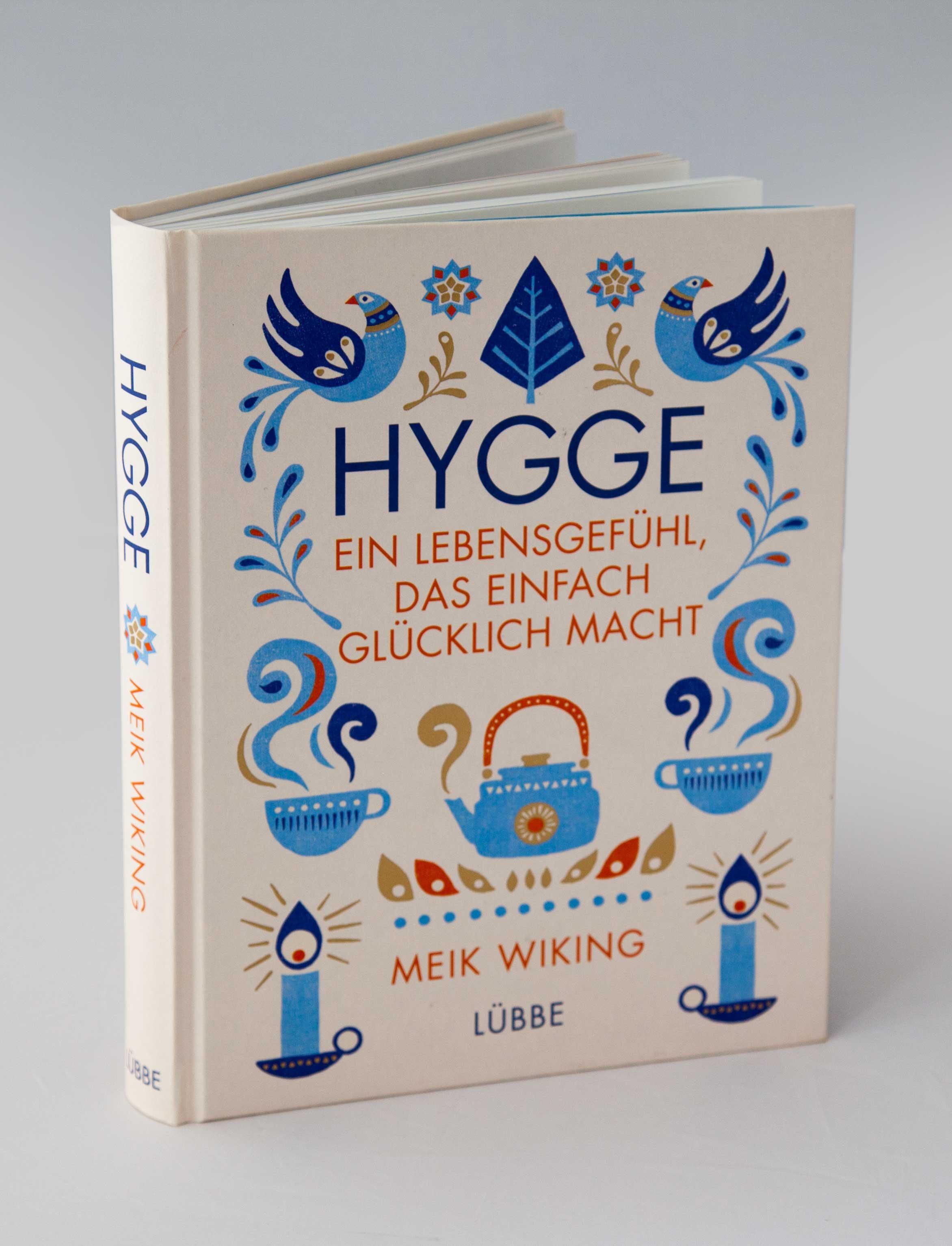 Buch mit Titel "Hygge - ein Lebensgefühl, das einfach glücklich macht". Illustrationen: Vögel, Teekanne, Tassen, Kerzen. Autor: Meik Wiking.