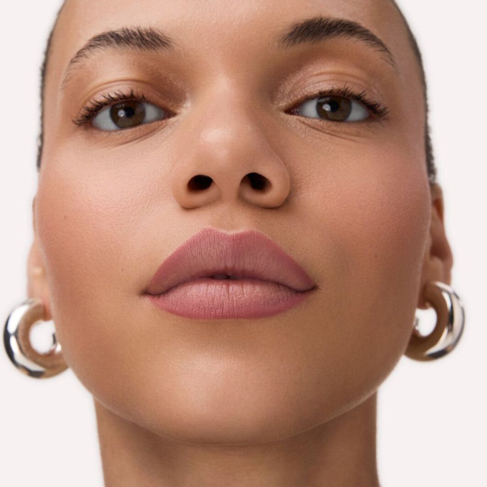 Nahaufnahme eines Gesichts mit geschminkten Lippen. Rosa Lippenstift, helle Haut, silberne Creolen.