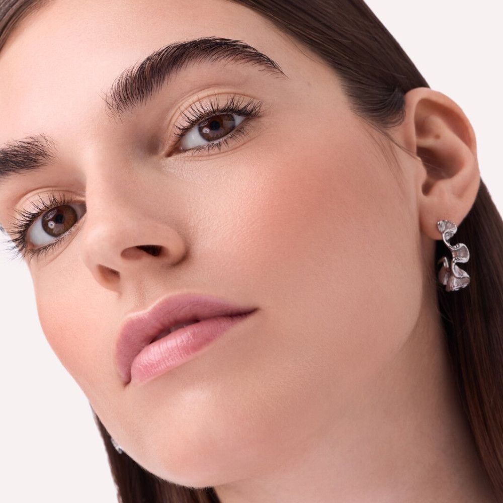 Nahaufnahme einer Frau mit Rouge auf den Wangen. Sie trägt Ohrringe. Natürliches Licht.