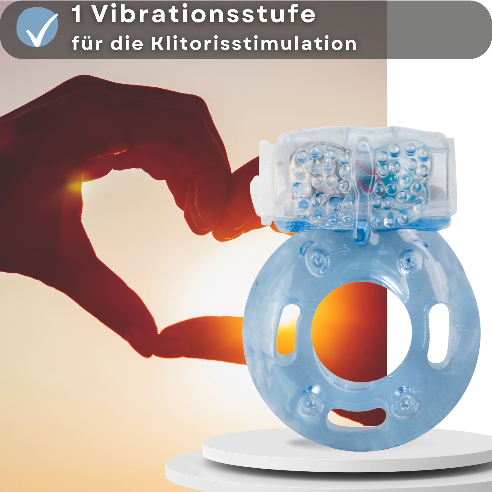 Hand formt Herz. Penisring mit 1 Vibrationsstufe für Klitorisstimulation. Produkt auf Podest.