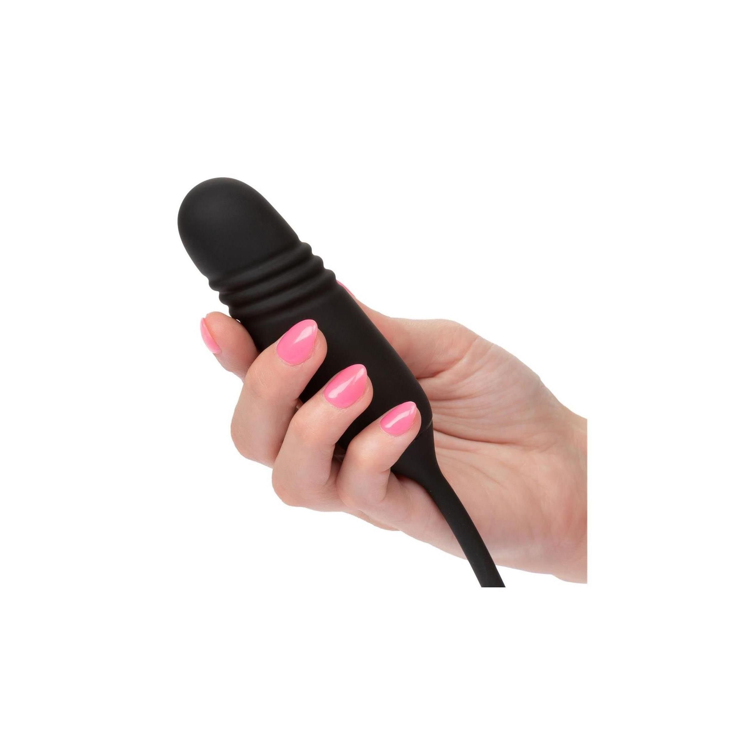 Schwarzer Vibrator in einer Hand gehalten. Rosa lackierte Fingernägel. Glatte, zylindrische Form.