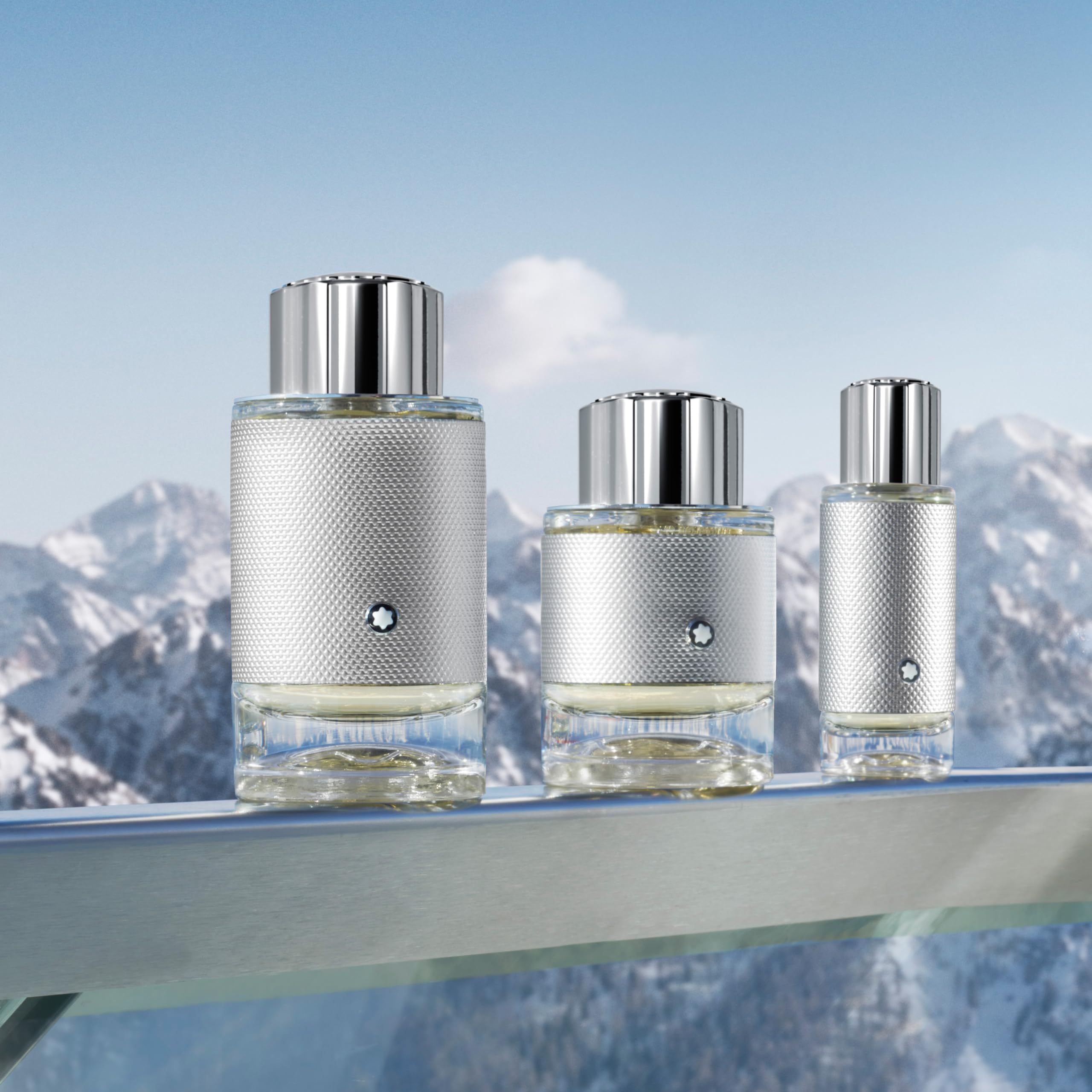 Drei Parfümflakons mit silberfarbenen Deckeln vor Bergpanorama. Montblanc-Logo auf jedem Flakon.