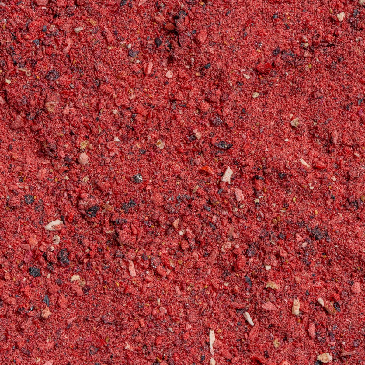 Nahaufnahme von rotem Fruchtpulver. Die Textur ist körnig und besteht aus kleinen, unregelmäßigen Partikeln.