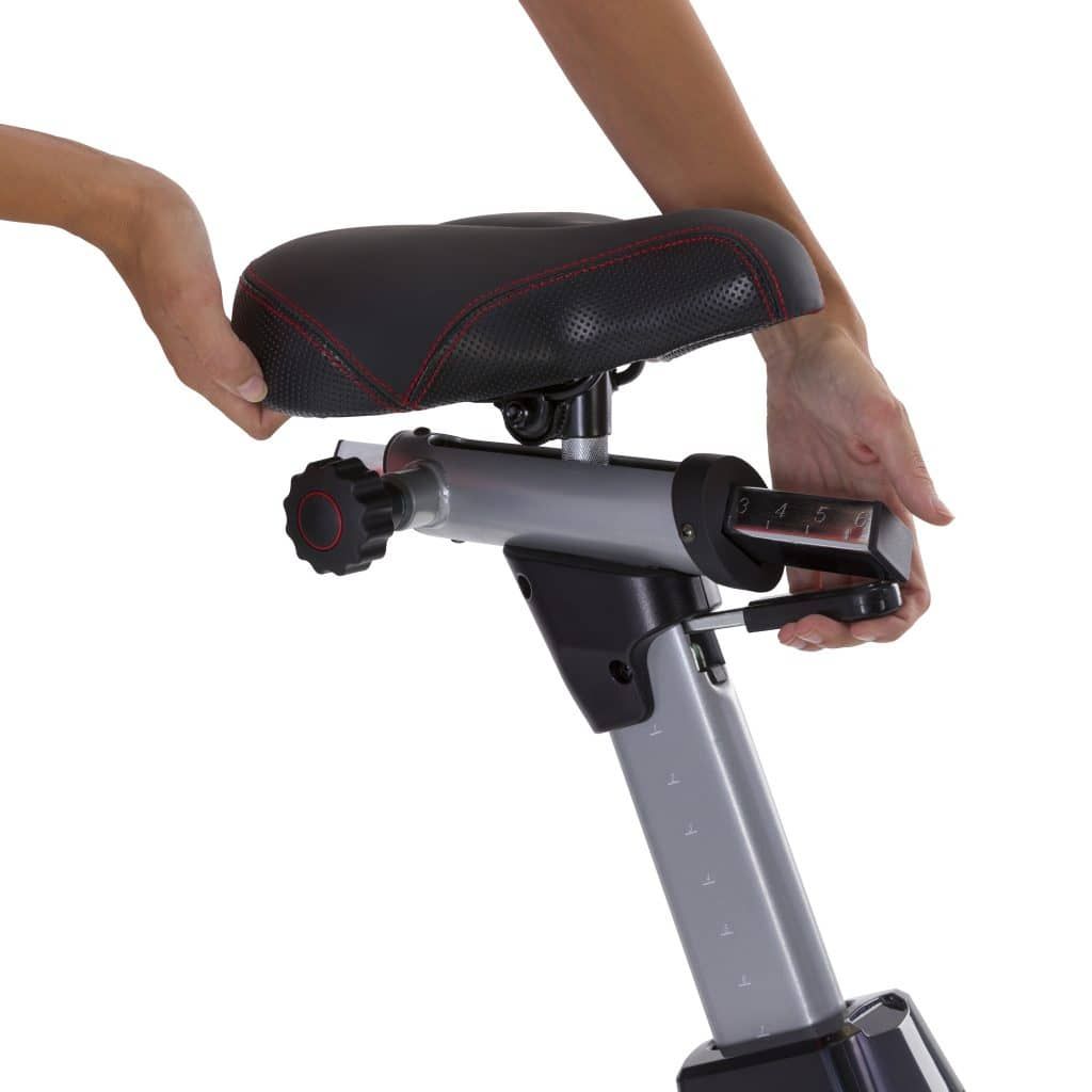 Nahaufnahme des Sitzes eines Airbikes. Schwarzer Sitz mit roten Nähten. Einstellmechanismus.