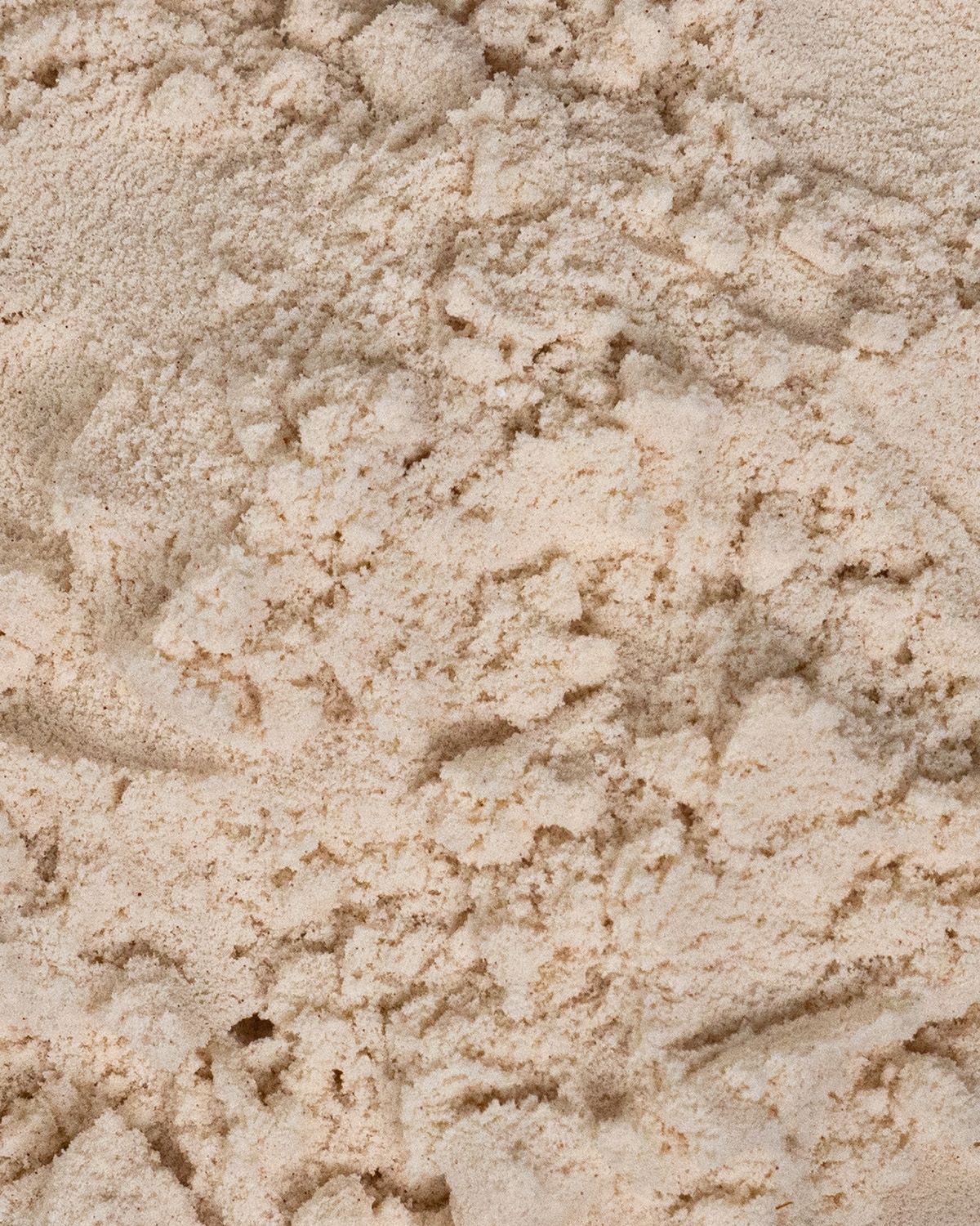 Nahaufnahme von Proteinpulver. Helle, beige Farbe. Grobkörnige Textur.