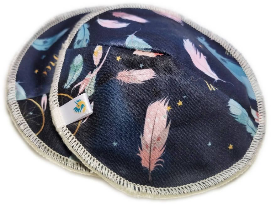 Zwei runde Stilleinlagen mit Feder-Muster. Dunkelblauer Stoff mit Federn in Rosa, Blau und Grün. Weißer Rand und Etikett.