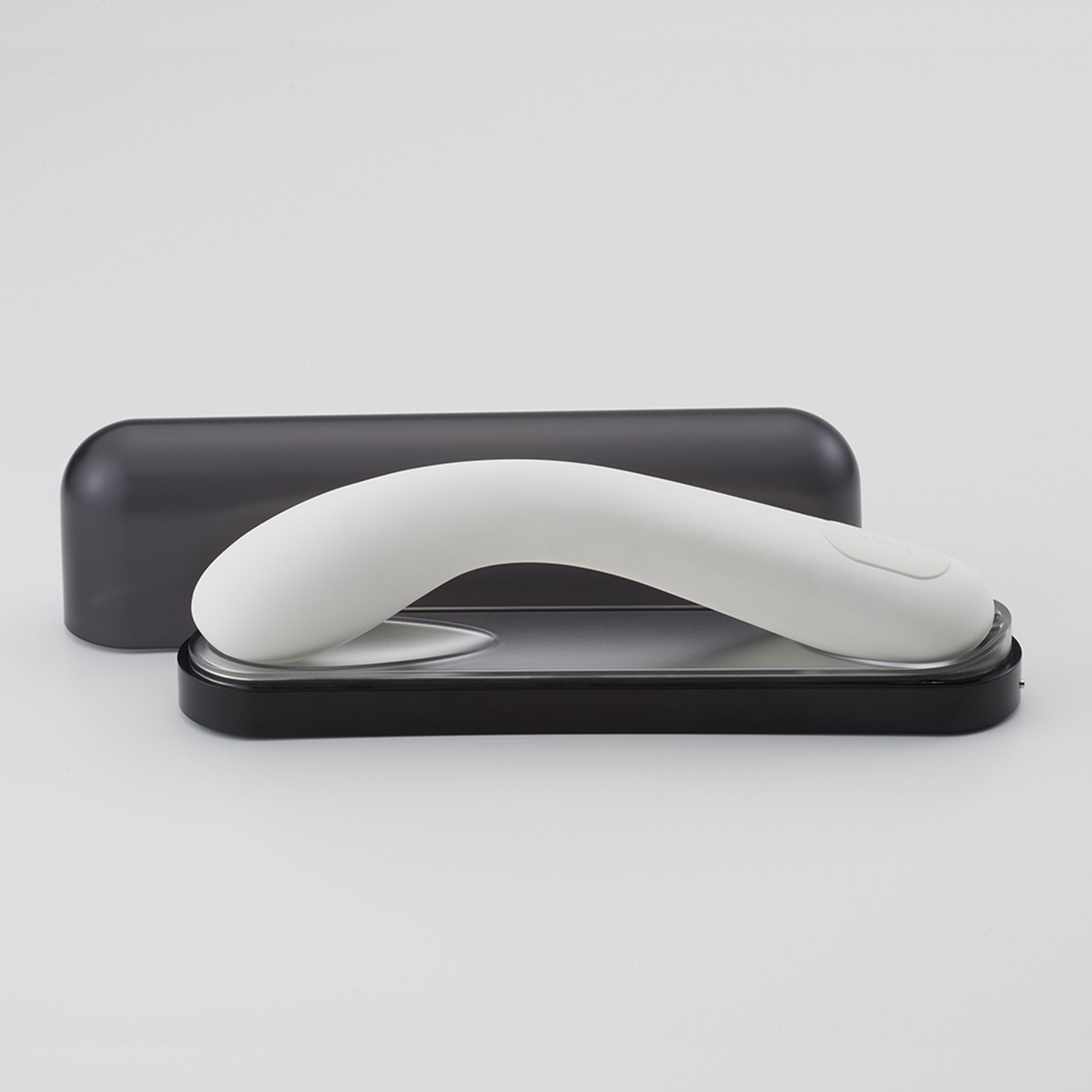 Weißes, geschwungenes Wellness-Produkt auf schwarzer Basis, daneben eine schwarze Hülle. Minimalistisches Design.