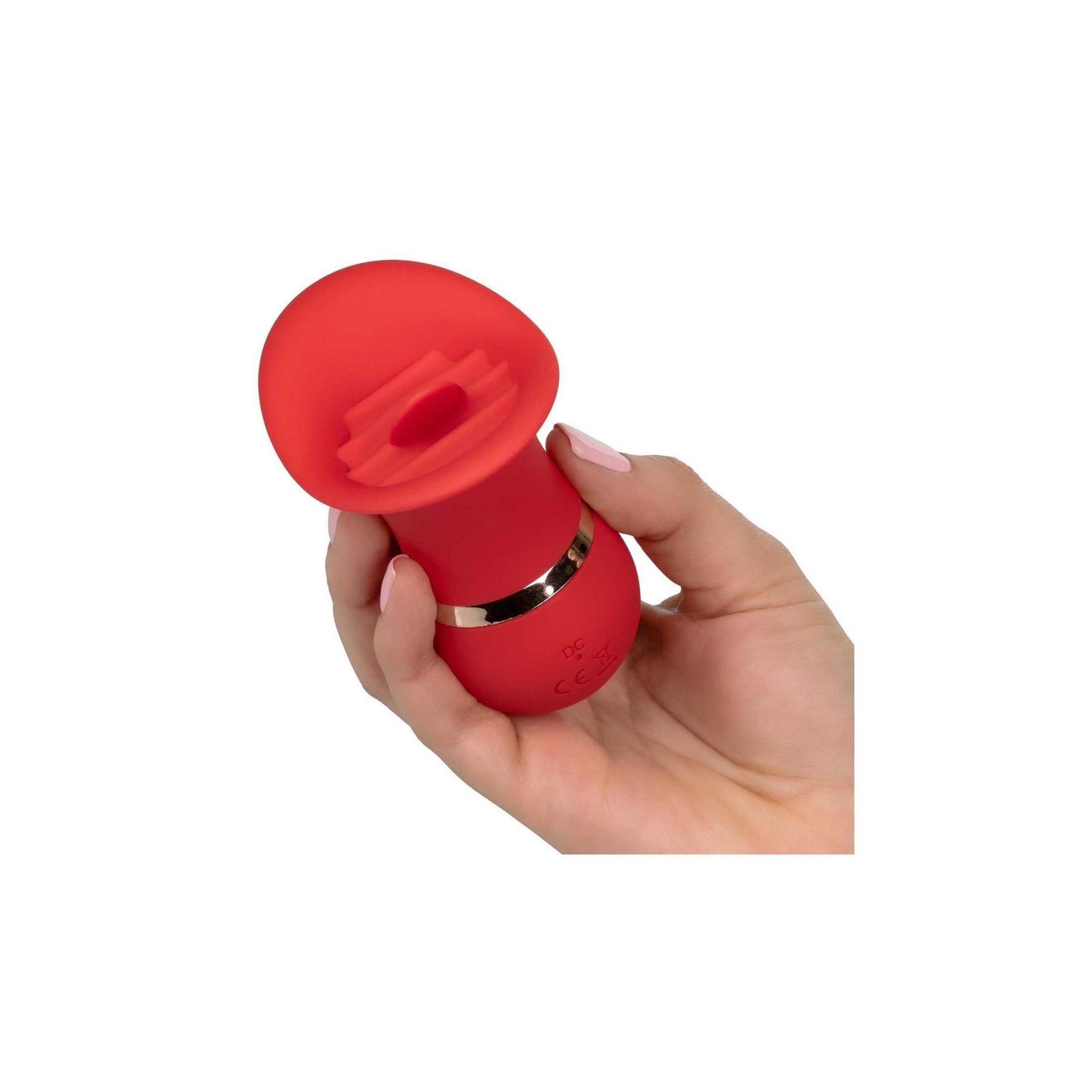 Roter Charmer in Hand gehalten. Goldfarbener Ring. Oberteil mit geriffelter Öffnung. Gehalten von einer Hand mit rosa Fingernägeln.