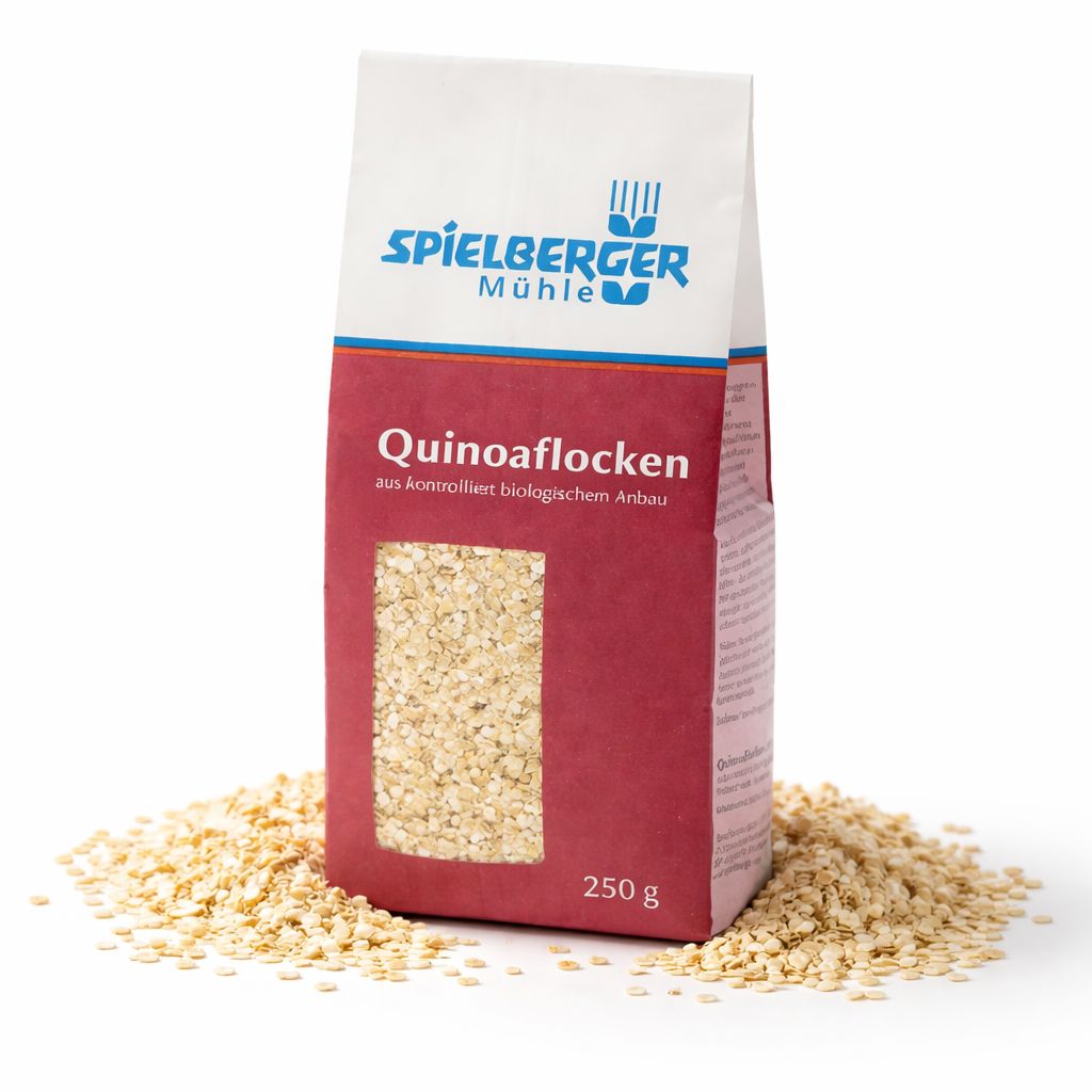 Packung Spielberger Quinoaflocken glutenfrei, 250g, umgeben von verstreuten Quinoaflocken.