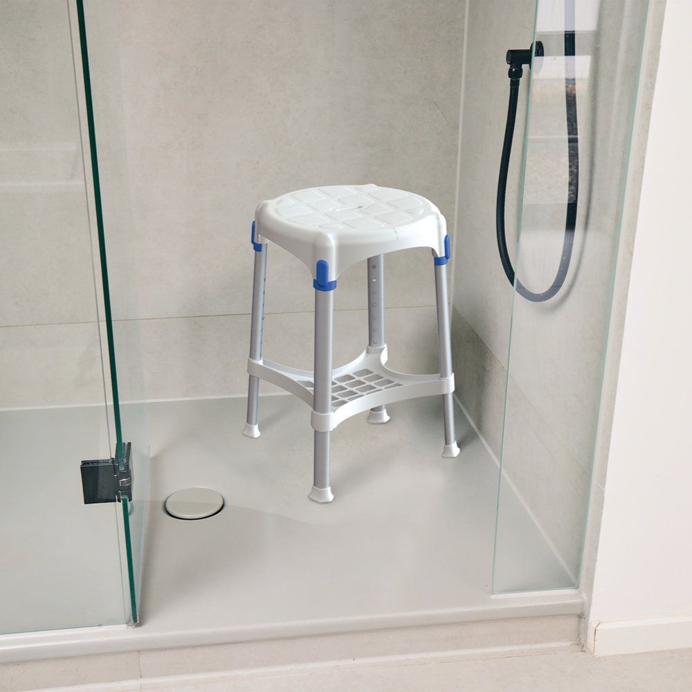 Runder Duschhocker mit Ablage. Weißer Sitz, blaue Akzente, silberne Beine. Steht in einer Dusche.