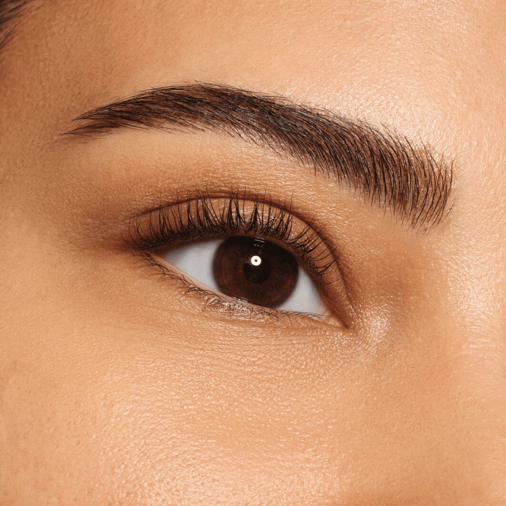Nahaufnahme eines Auges mit perfekt geformten Augenbrauen und Wimpern. Braune Augenfarbe.