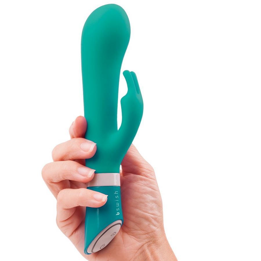 Grüner Silikonvibrator in einer Hand. Der Vibrator hat eine gebogene Form und eine Kaninchenform.