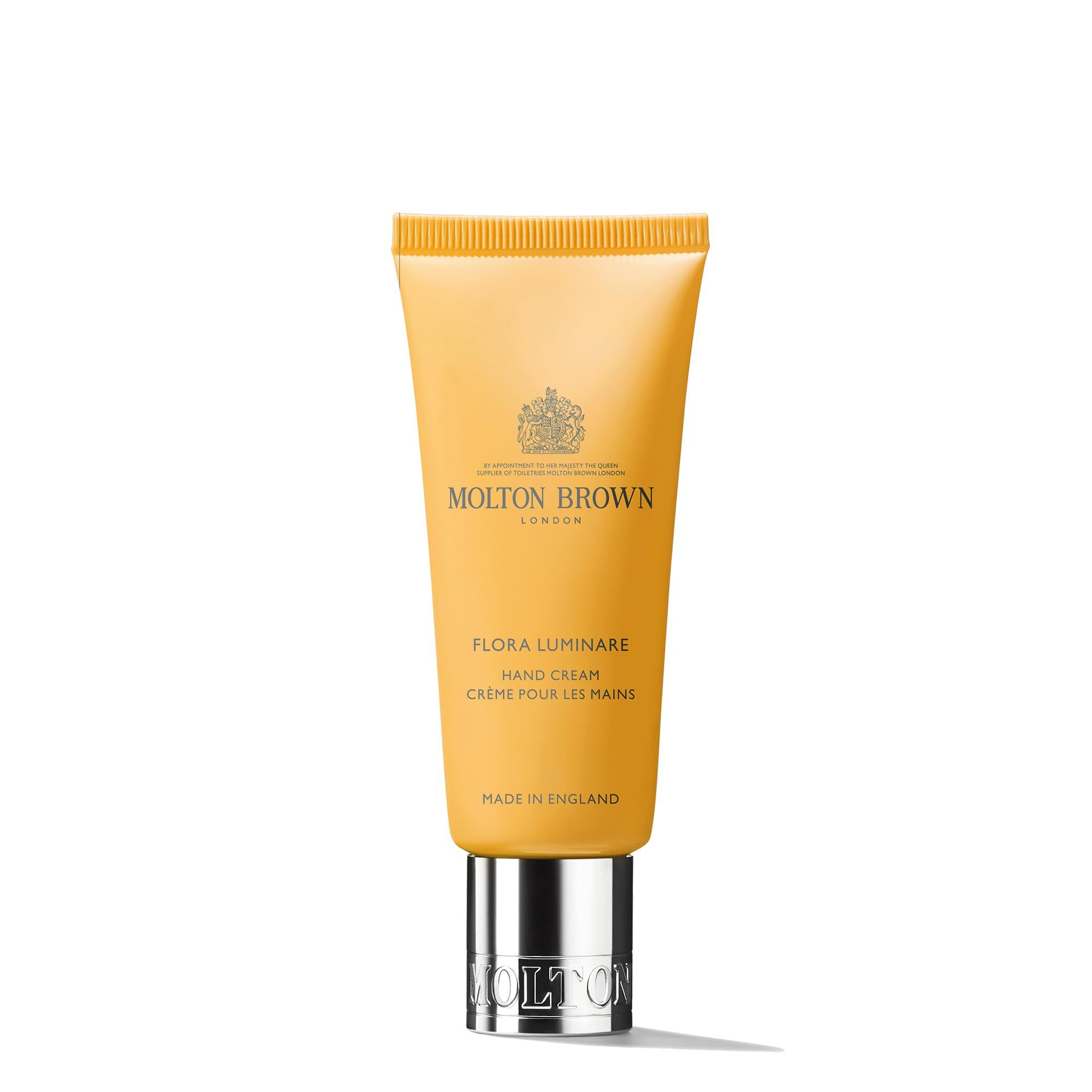 Gelbe Tube Handcreme. Aufschrift: Molton Brown, Flora Luminare Hand Cream, Crème pour les mains. Silberner Verschluss.