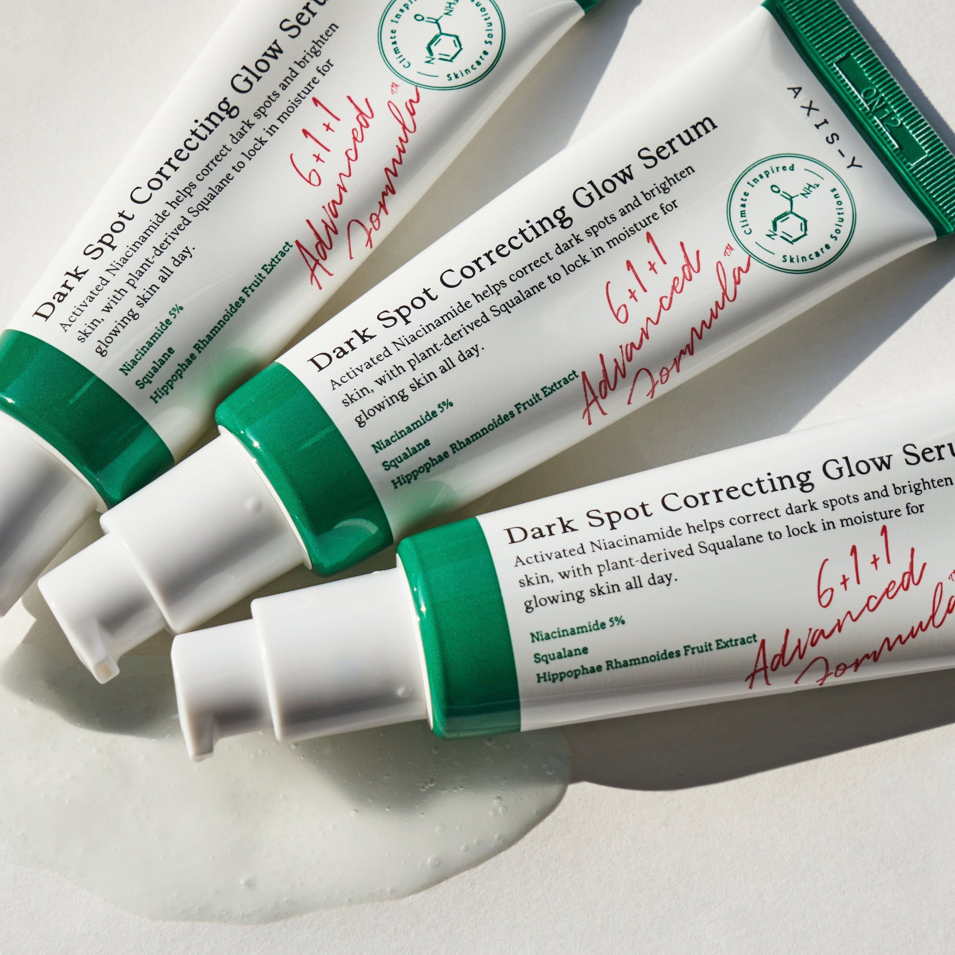 Mehrere Tuben Serum. Aufschrift: Dark Spot Correcting Glow Serum. Marke: AXIS-Y. Produkt auf weißem Hintergrund.