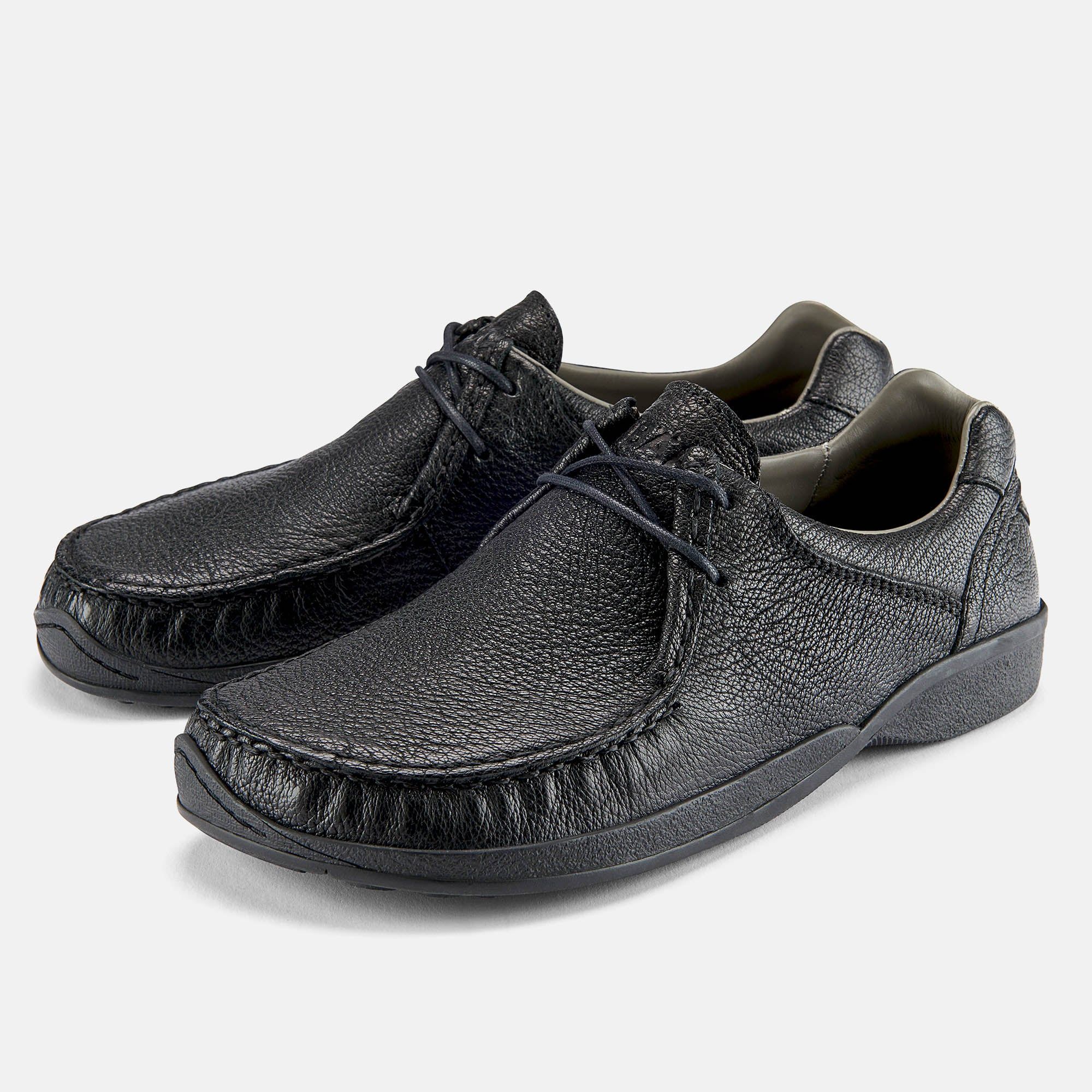 Schwarze Lederschnürschuhe. Breite Passform. Sichtbare Nähte. Schnürsenkel. Gummisohle. Hellgrauer Hintergrund.