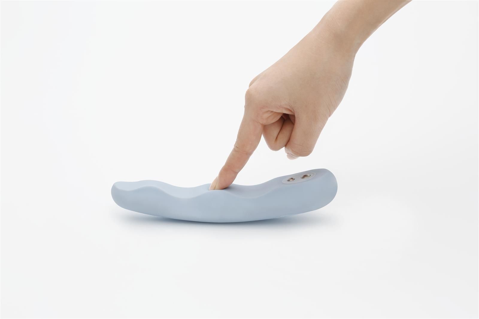 Hand berührt hellblauen Vibrator. Zwei Knöpfe sichtbar. Wellenförmige Oberfläche.
