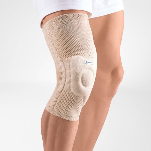 Beige Kniebandage am Bein getragen. Polsterung um die Kniescheibe. Keine Marke sichtbar.