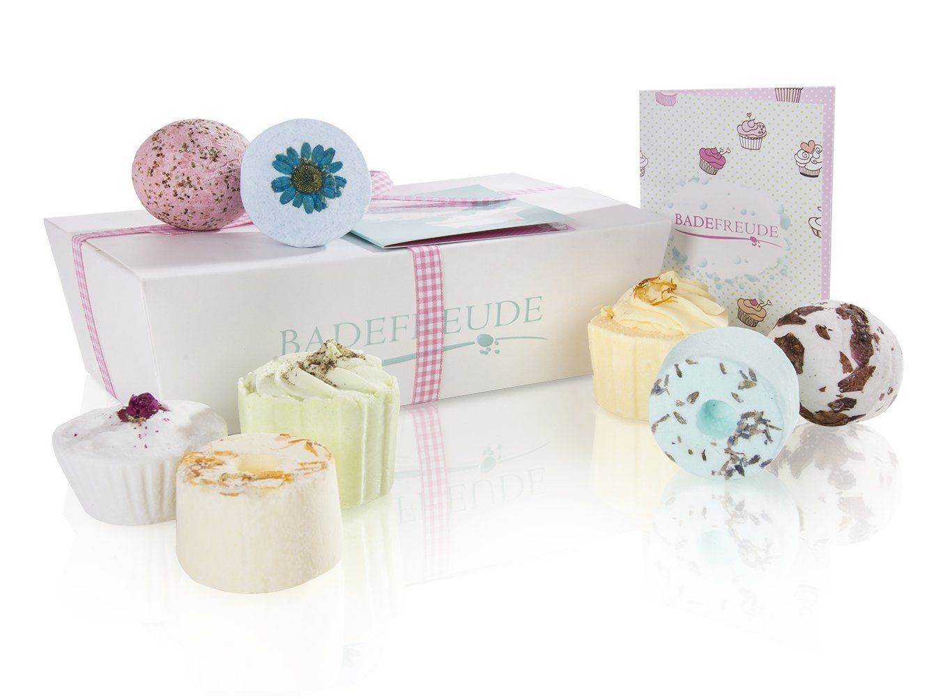 Verschiedene Badebomben und -kuchen in einer weißen Geschenkbox. Einige sind rund, andere cupcake-förmig. Aufdruck "Badefreude".