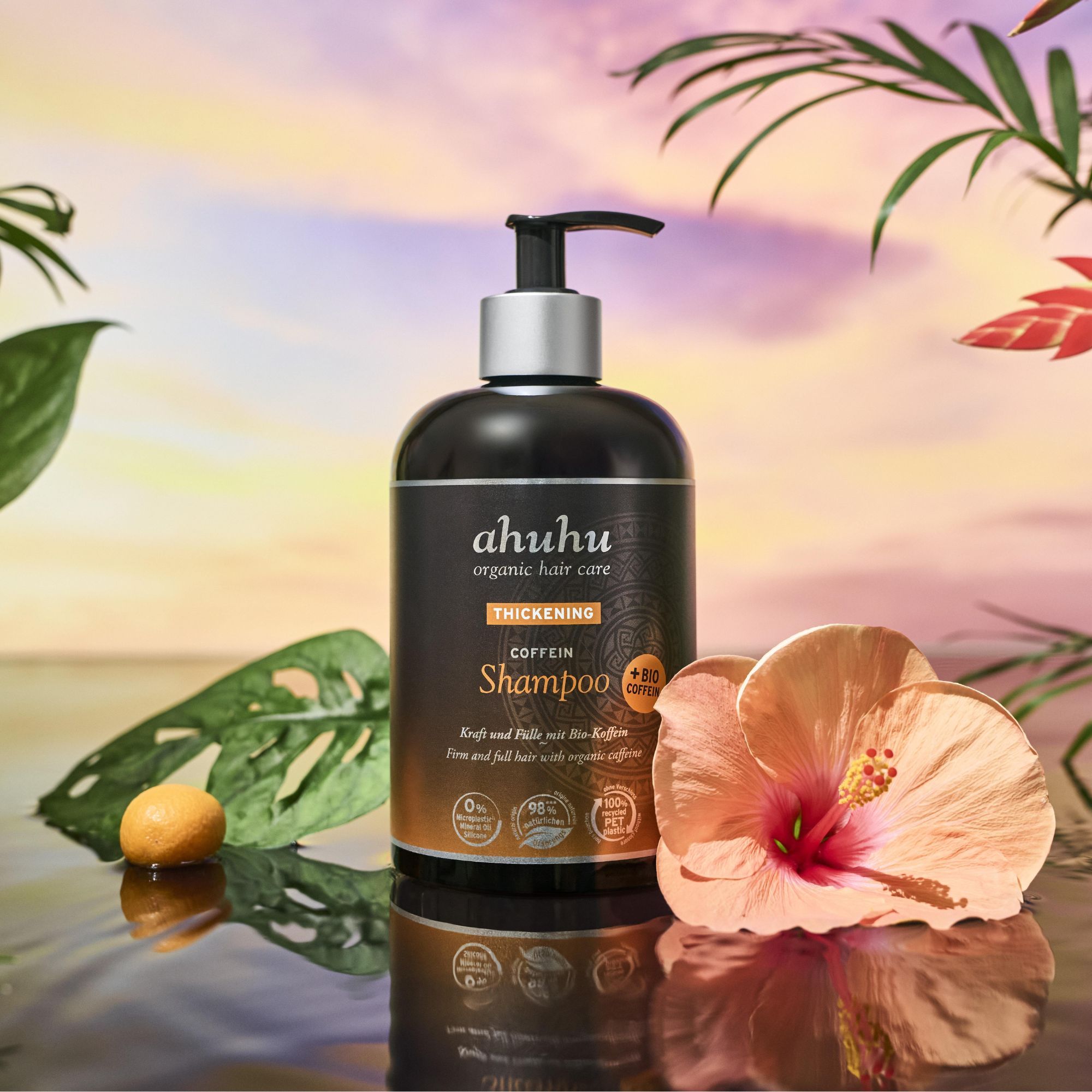 Shampoo-Flasche vor tropischer Kulisse. Aufschrift: ahuhu organic hair care, Thickening Coffein Shampoo. Mit Bio-Koffein. Siegel: 0% Silikone, 98% natürliche Inhaltsstoffe, 100% recyceltes PET.