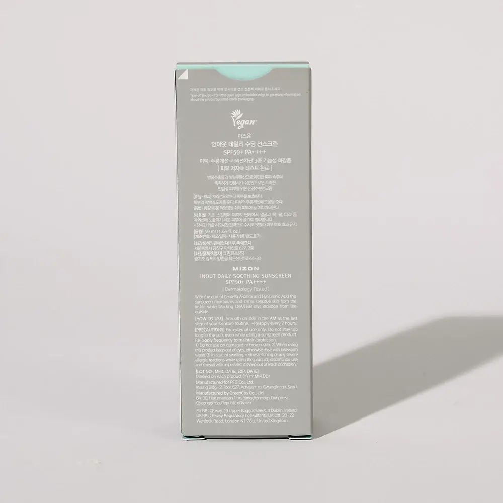 Graue Produktverpackung. Schriftzug: MIZON, INOUT DAILY SOOTHING SUNSCREEN. Text in mehreren Sprachen. Schatten.