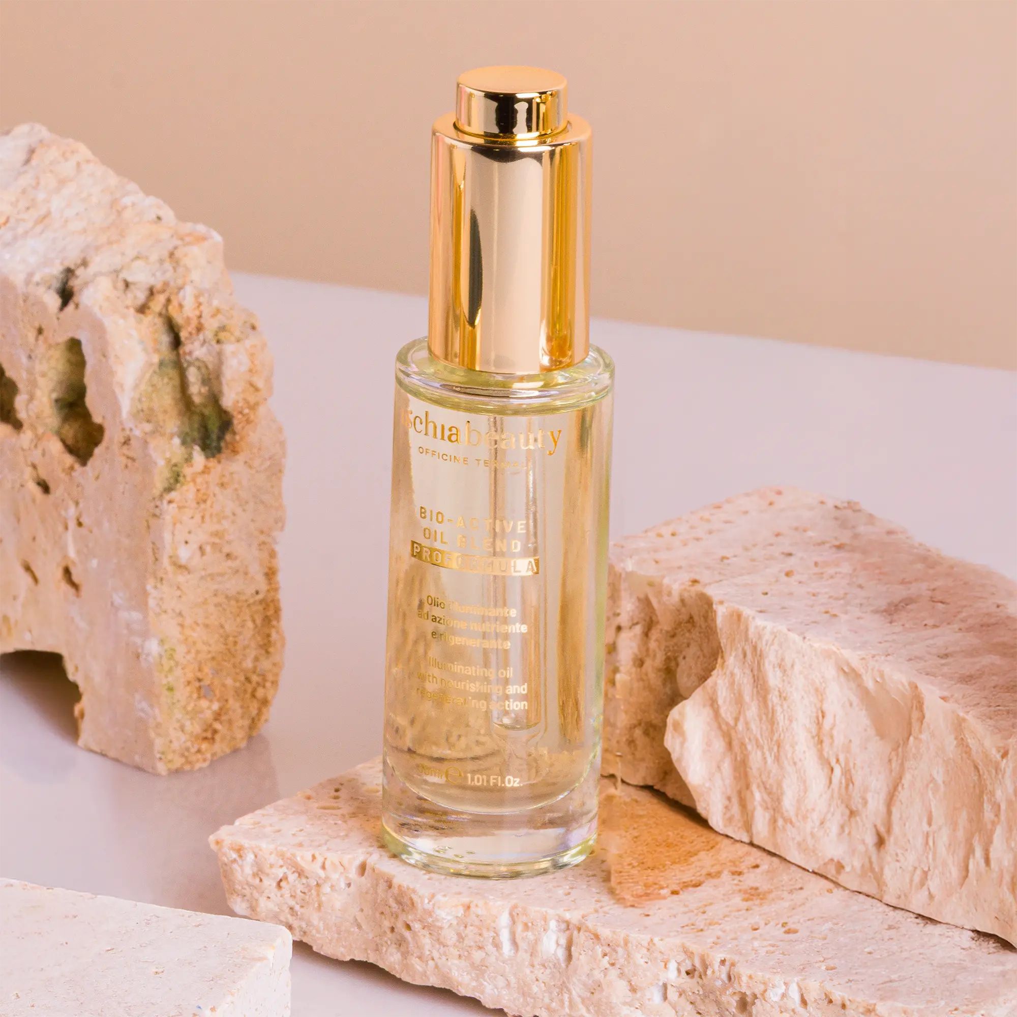 Glasflasche mit goldfarbenem Verschluss. Aufschrift: ischiabeauty, BIO-ACTIVI OIL BLEND. Klarer Inhalt, platziert auf Steinblöcken.