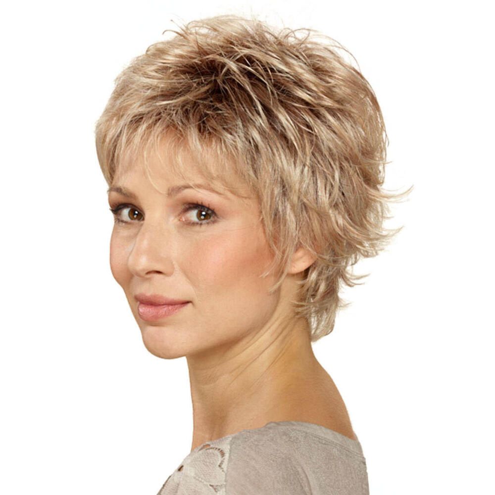 Kurzhaarperücke in Blondtönen. Die Frau trägt ein graues Oberteil. Seitenansicht.