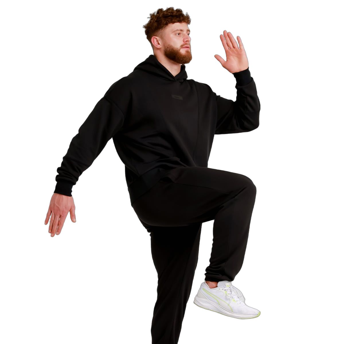 Mann in schwarzer Jogginghose und Kapuzenpullover, hebt ein Bein.