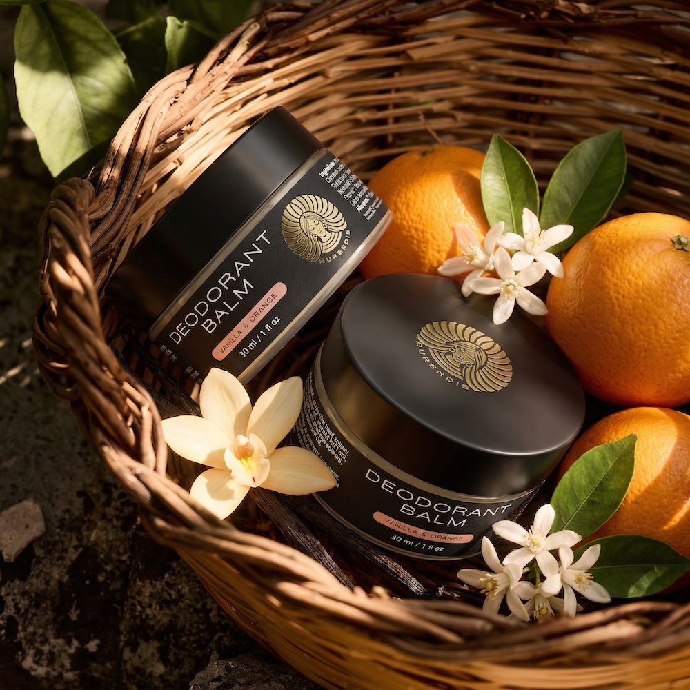 Zwei schwarze Deocreme-Tiegel in einem Weidenkorb mit Orangen, Blüten und Blättern. Aufschrift: Deodorant Balm.