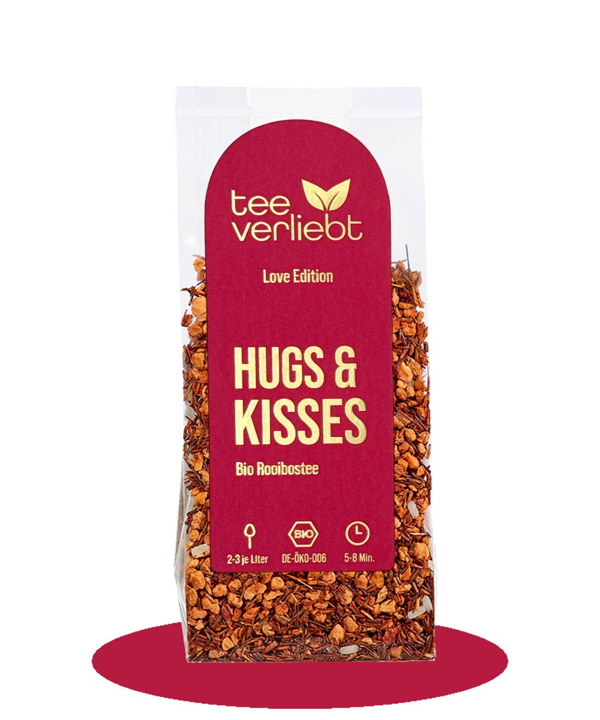 Verpackung mit losem Tee. Roter Aufkleber mit "tee verliebt" und "HUGS & KISSES" Schriftzug. Bio-Siegel.