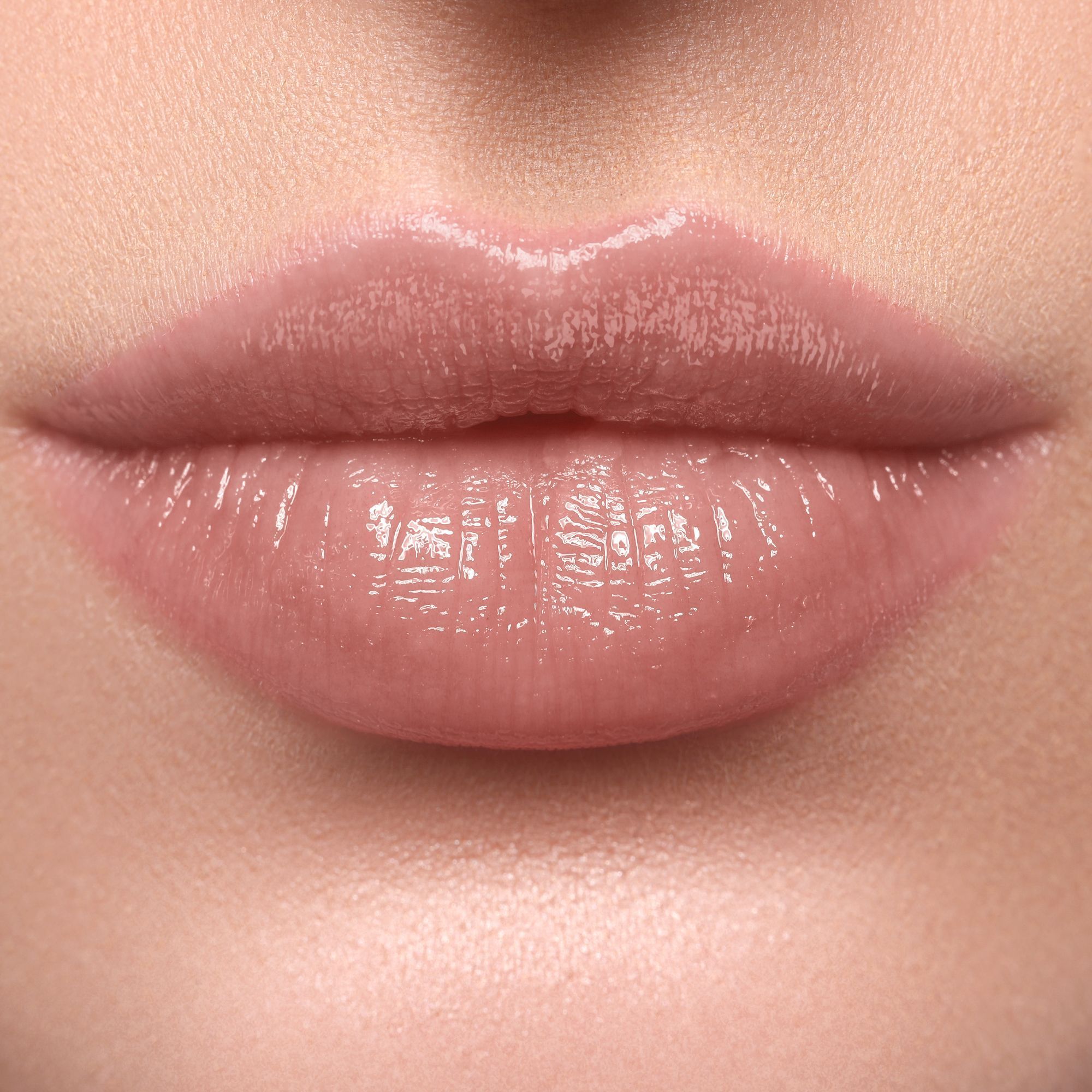 Nahaufnahme von Lippen mit glänzendem, rosafarbenem Lippenstift. Die Lippen sind leicht geöffnet.