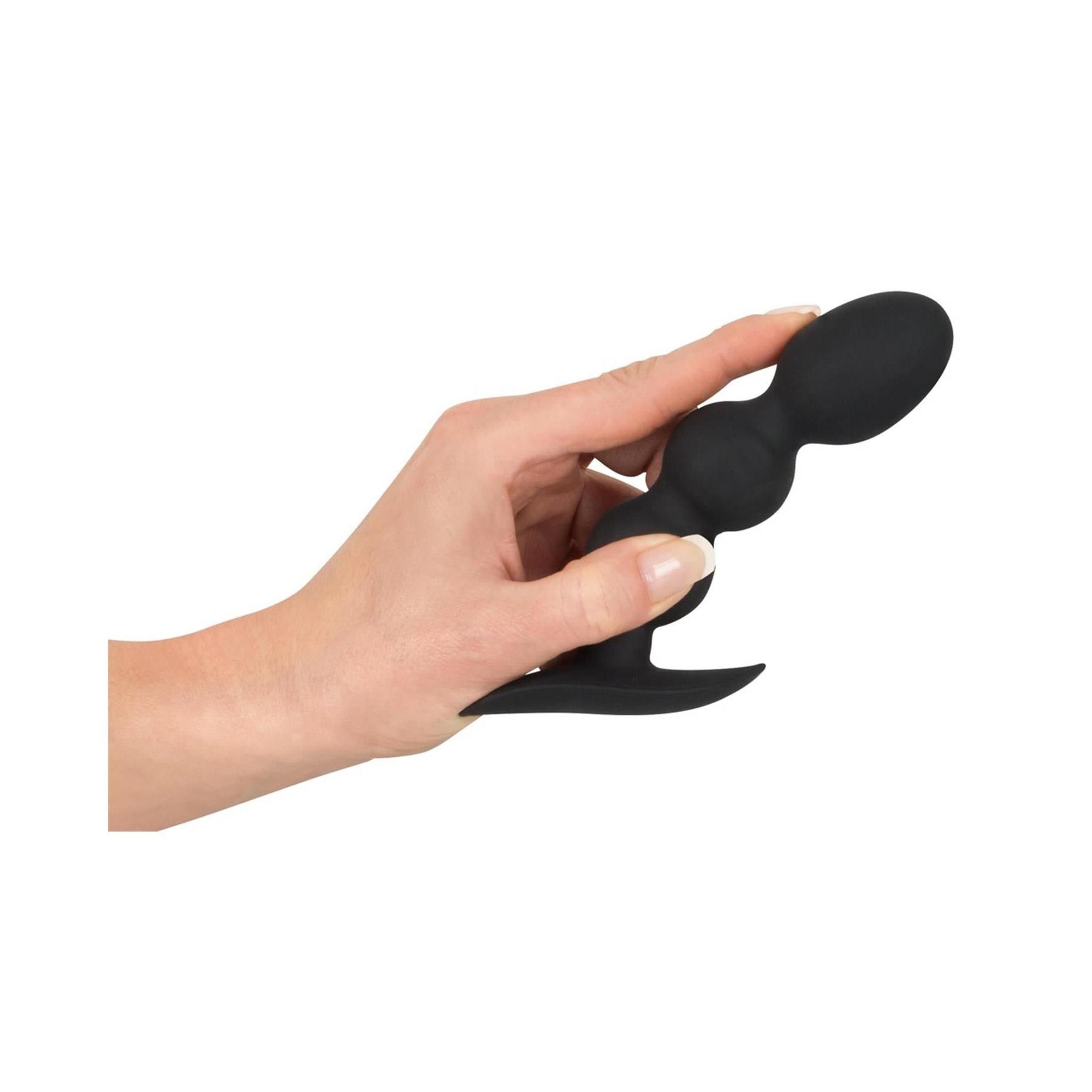 Schwarzes Analspielzeug mit drei Kugeln, gehalten von einer Hand. Aus Silikon.