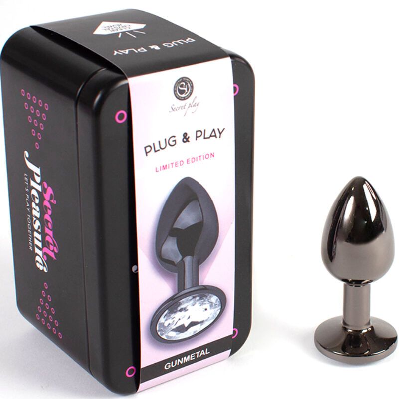 Gunmetal Butt Plug Kleine Größe neben schwarzer Dose. Dose mit Aufdruck "Plug & Play" und Logo. Plug mit Kristall.