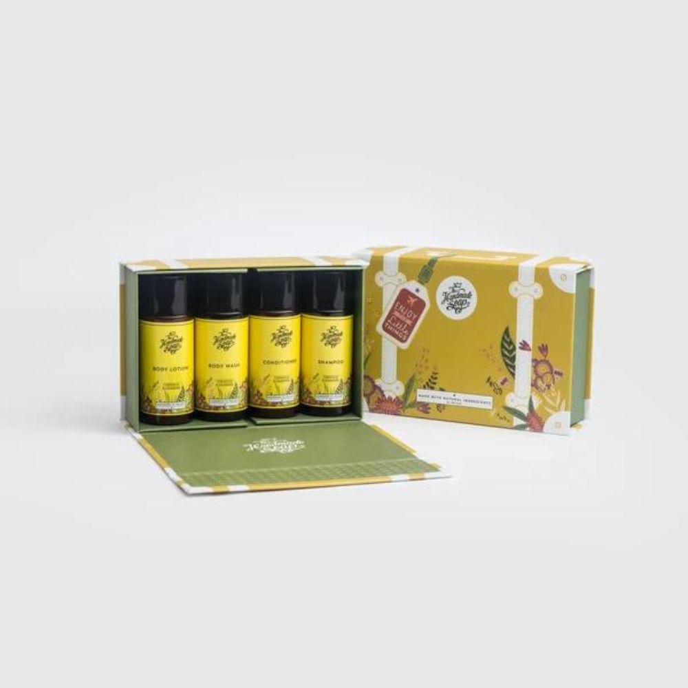 Reiseset mit vier Flaschen in einer gelben Kofferbox. Aufschrift: Body Lotion, Body Wash, Treatment, Nourish. Mit Anhänger.