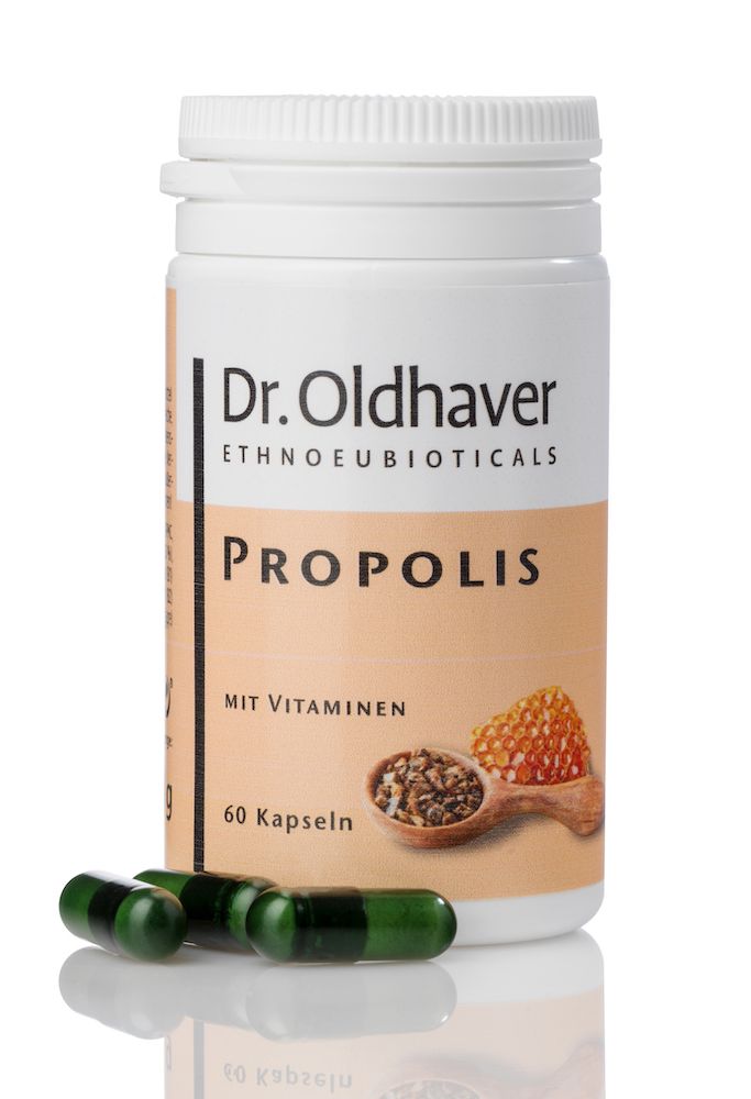 Weiße Dose mit grünen Kapseln. Aufschrift: Dr. Oldhaver Propolis mit Vitaminen. Abbildung von Propolis und Honigwabe.