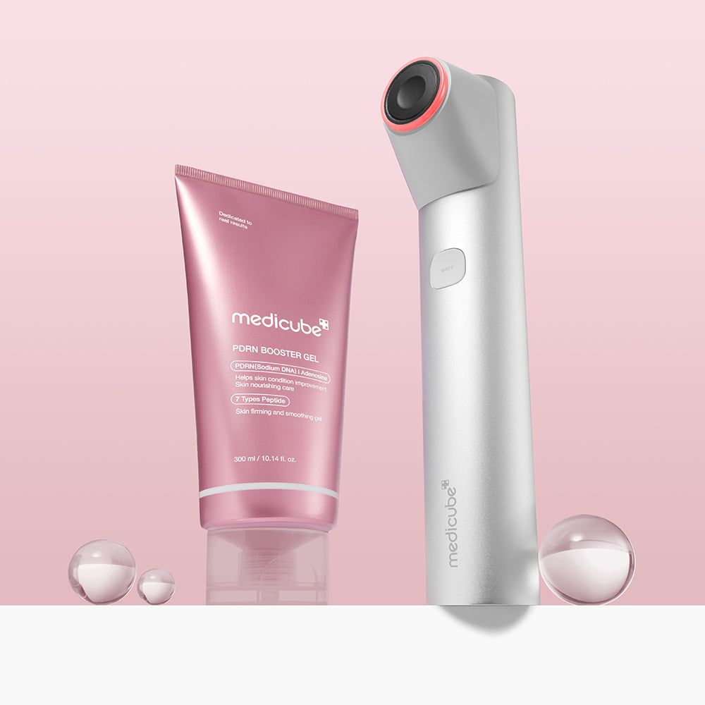 Rosa Tube MEDICUBE PDRN Booster Gel und weißes Gerät. Beide auf rosa Hintergrund. Kugeln.