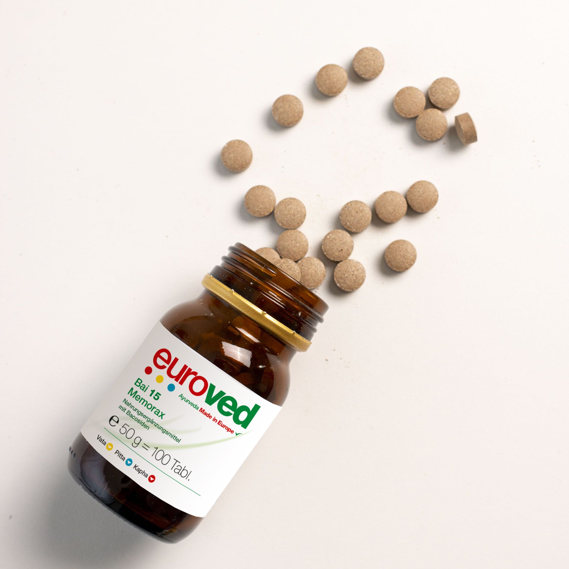 Geöffnete braune Glasflasche mit goldfarbenem Deckel. Tabletten liegen daneben. Weißes Etikett mit rotem "euroved"-Logo und Produktbezeichnung.