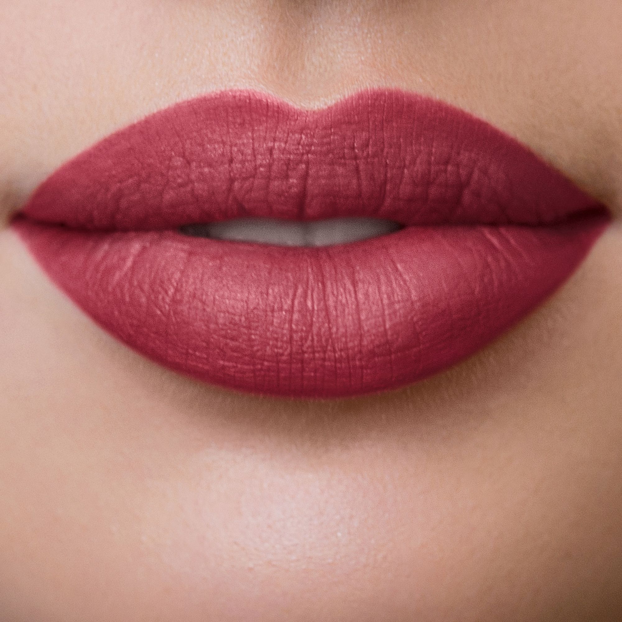 Nahaufnahme von Lippen, die mit Marsala-farbenem Lippenstift geschminkt sind. Matte Oberfläche.