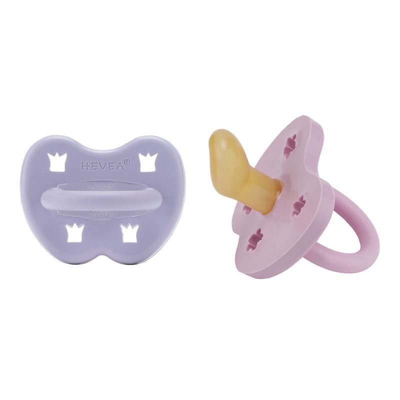 Lila Schnuller mit HEVEA-Logo. Rechts, ein Schnuller mit gelbem Sauger und rosa Ring.