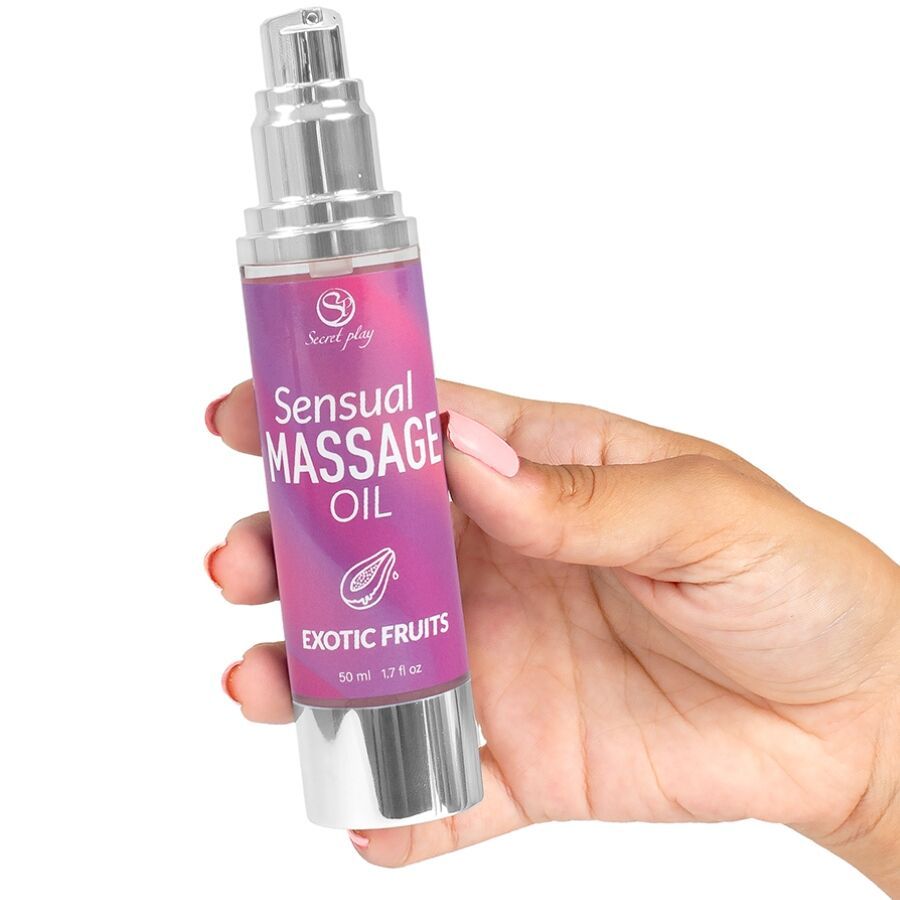 Flasche mit Massageöl. Aufschrift: Sensual Massage Oil Exotic Fruits. In Hand gehalten.