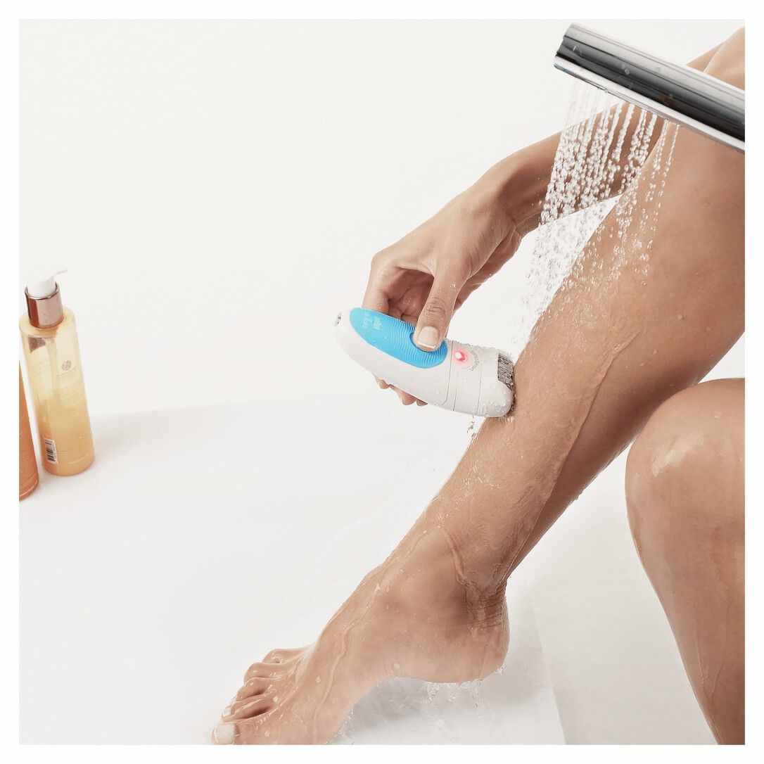 Person epiliert Bein unter der Dusche. Epilierer ist weiß-blau.