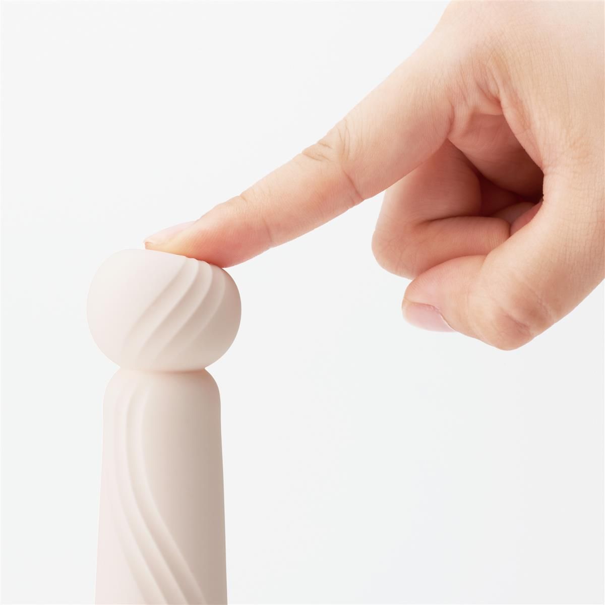 Nahaufnahme: Finger berührt den gerillten Kopf eines weißen Vibrators. iroha-Produkt.