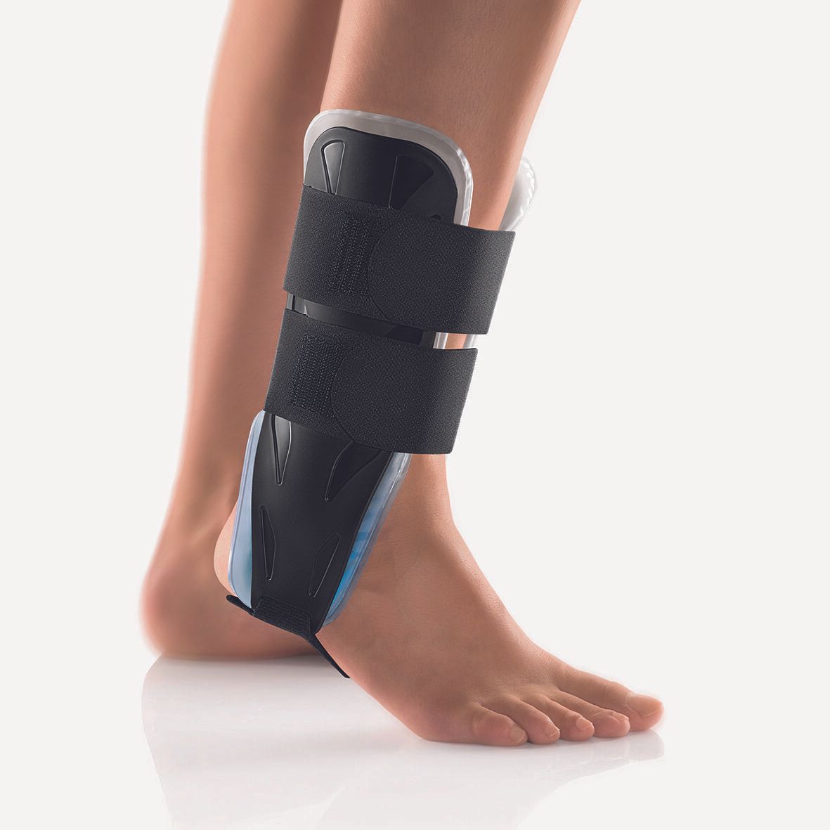 Knöchelorthese am Bein. Schwarze Orthese mit Klettverschlüssen und blauem Gel. Fuß in Seitenansicht.