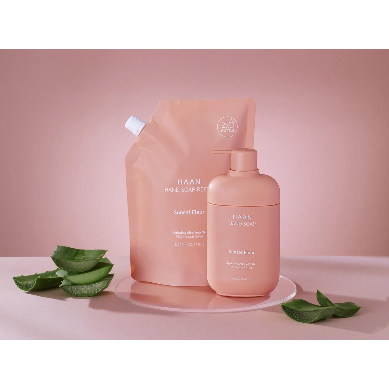 Rosa Handseife und Nachfüllbeutel. Text: HAAN, Sunset Fleur. Aloe Vera Gel. Auf rosa Untergrund. Aloe Vera Blätter.