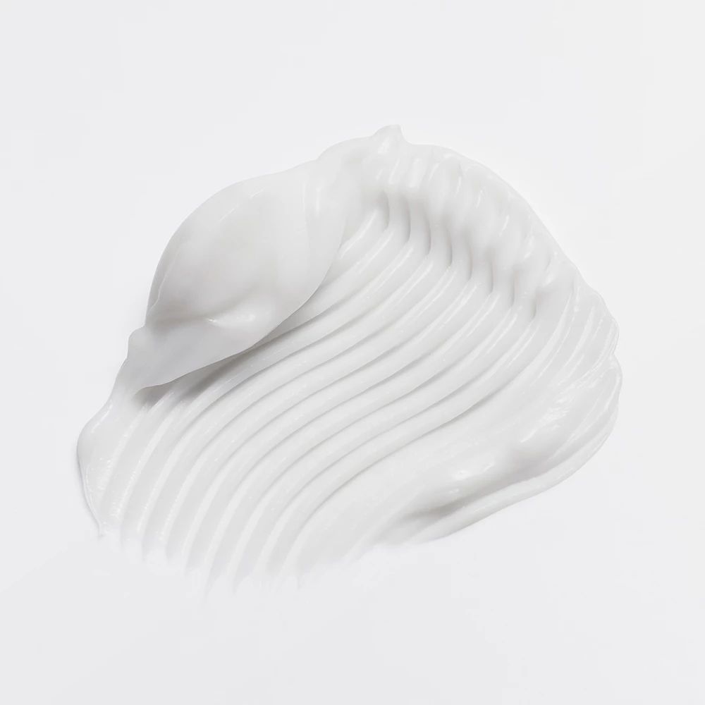 Nahaufnahme von weißer Creme. Creme in wellenförmigen Linien auf hellem Hintergrund.