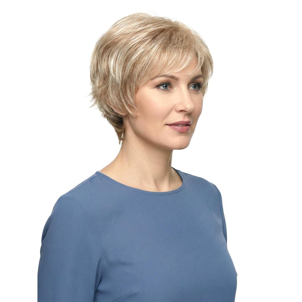 Kurzhaarperücke in Blondtönen. Dreiviertelansicht einer Frau mit Perücke und blauem Oberteil.